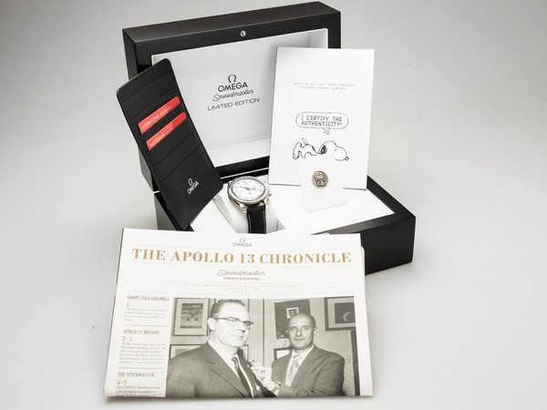 Geöffnete Omega-Box der Speedmaster Silver Snoopy Award von 2015 mit Uhr, Kartenetui, Snoopy-Zertifikat mit Anstecknadel und Zeitung „The Apollo 13 Chronicle“