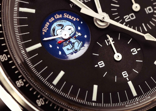 Nahaufnahme des schwarzen Speedmaster-Zifferblatts mit Snoopy im Raumanzug und dem Schriftzug „Eyes on the Stars“ im Hilfszifferblatt bei 9 Uhr