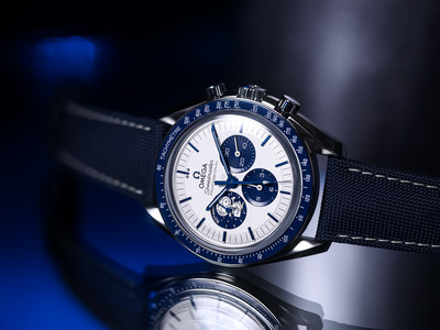 Speedmaster Silver Snoopy Award 50th Anniversary schräg von vorn auf dunkler, spiegelnder Fläche mit blauem Licht