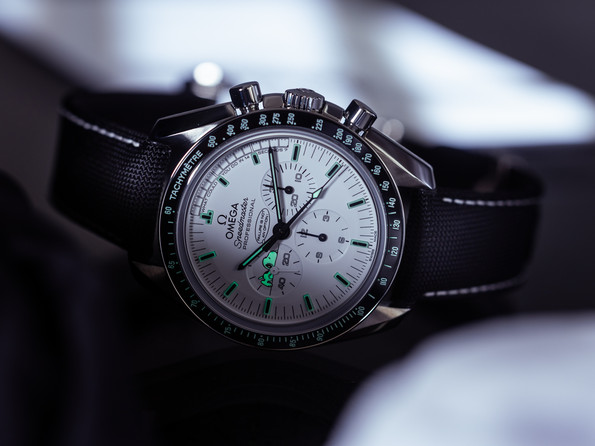 Speedmaster Silver Snoopy Award von 2015 mit weißem Zifferblatt, schwarzer Tachymeter-Lünette und schwarzem Textilband; Indizes, Zeiger und Snoopy bei 9 Uhr leuchten grün